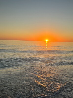 A sunset over a calm sea with gentle waves.