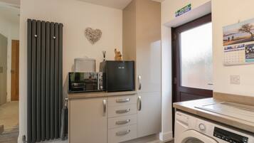 A compact kitchen with a microwave, toaster, and a washing machine.