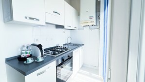 Une cuisine moderne avec des meubles blancs, une cuisinière à gaz, un évier et un four encastré.