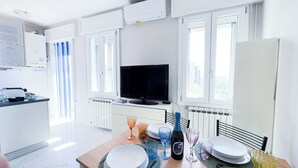 Une cuisine moderne avec des armoires blanches, une cuisinière encastrée et un téléviseur à écran plat.