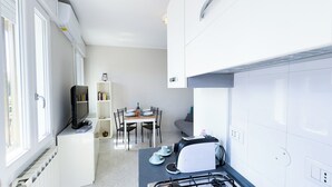 Une cuisine compacte avec un coin repas, un téléviseur encastré et une bibliothèque.