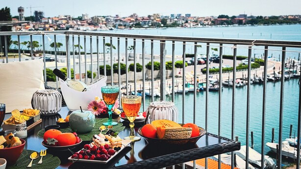 Ein Balkon mit Frühstückstisch mit Blick auf einen Yachthafen, Boote und eine Stadtansicht.
