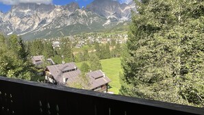 Une vue sur la montagne depuis un balcon doté d’une balustrade, avec un village et des montagnes en contrebas.