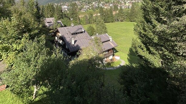 Un village de montagne aux maisons traditionnelles, avec un ciel dégagé et une vue sur les sommets environnants.