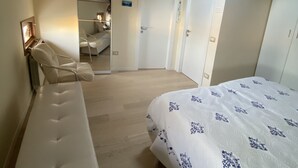 A bedroom with a bed, a chair, a mirror, and a door.