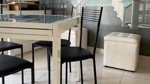 A room with a beach mural, a dining table with chairs, a TV, and a cushioned bench.