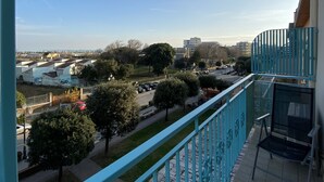 A balcony with a view of a cityscape, including buildings and trees.