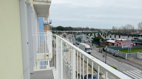 Ein Balkon mit Blick auf eine Straße, einen Parkplatz und ein Gebäude mit einem Schild.