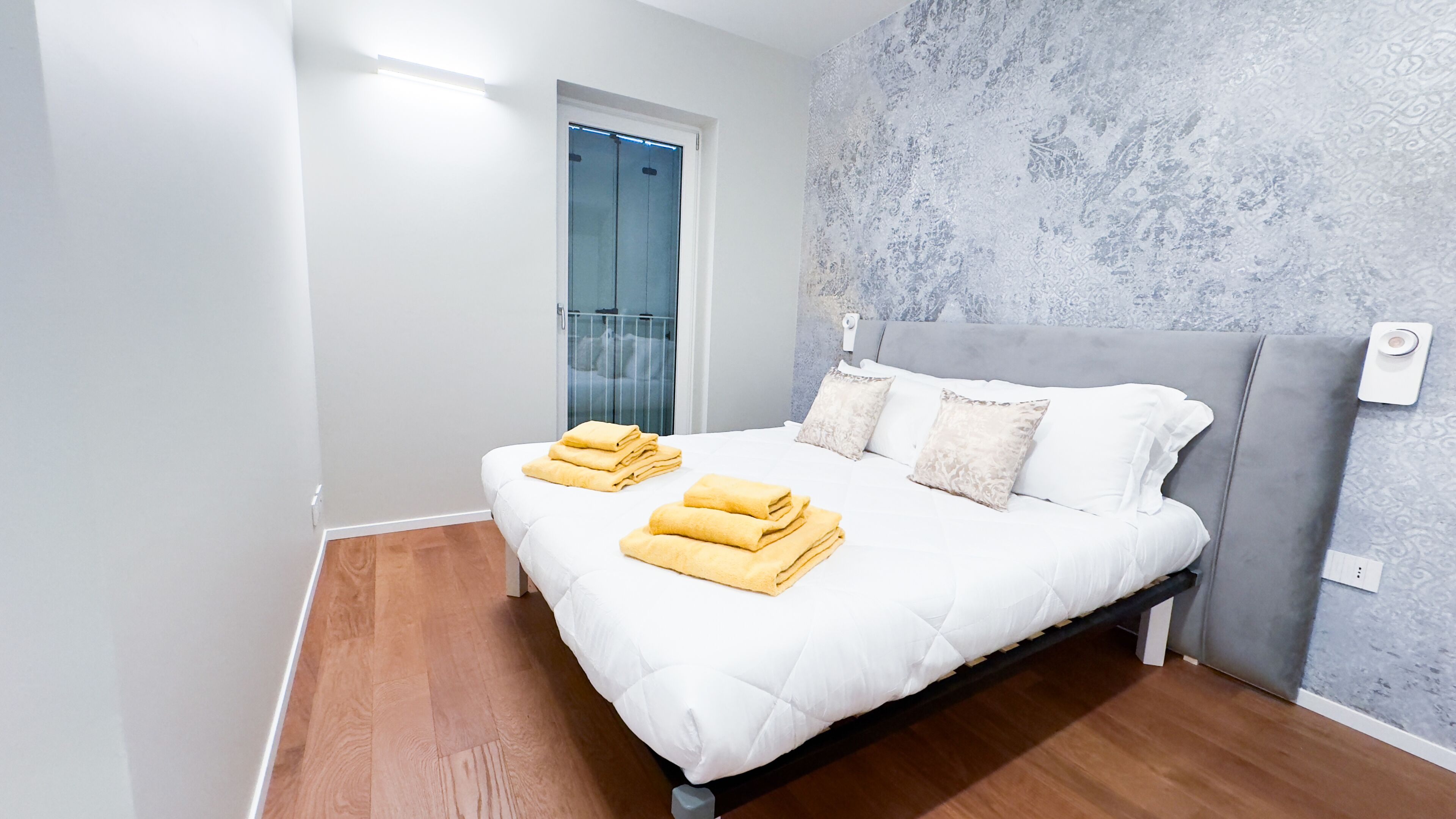 Une chambre à coucher moderne avec un lit, des oreillers et des serviettes soigneusement pliées.