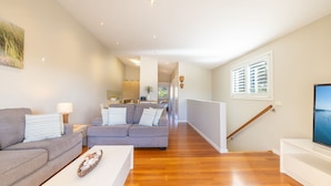 A modern living room with a grey sofa, a white coffee table, and a wooden floor. - Pet friendly La Costa, 2-1a Messines St - air con and Wi-Fi (Shoal Bay)