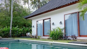 Ein modernes Haus mit Schwimmbad, umgeben von üppiger Vegetation und Palmen.