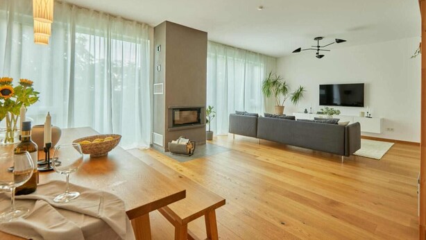 Un salon moderne avec une cheminée, un canapé, un téléviseur et un coin repas comprenant une table et des chaises.