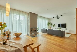 A modern living room with a fireplace, sofa, TV, and dining area with a table and chairs.