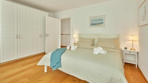 Une chambre à coucher avec un lit, deux tables de chevet avec des lampes, une armoire et un tableau au mur.