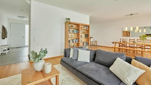 Un salon moderne avec un canapé gris, une table basse en bois et une bibliothèque.