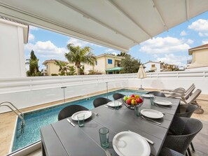 Ein Essbereich am Pool mit einem für zwei Personen gedeckten Tisch, einem Schwimmbad und Blick auf die Umgebung.