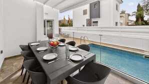 An outdoor dining area with a pool view, featuring a table set for four, chairs, and a decorative bowl. - Elite Luxury Villa / Private Pool / Privacy (Protaras)