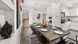 A modern kitchen with white cabinets, a wooden dining table, and a staircase leading to another level. - Elite Luxury Villa / Private Pool / Privacy (Protaras)
