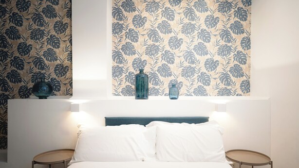 A bedroom with a bed, two bedside tables, and a wall with floral wallpaper. - IV HOUSE
Luxurious apartment in Rome (Roma)
