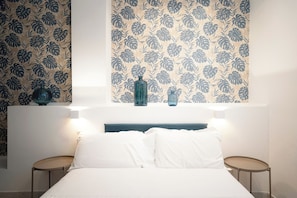 A bedroom with a bed, two bedside tables, and a wall with floral wallpaper.