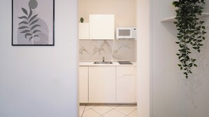 A modern kitchen with white cabinets, a marble backsplash, a microwave, and a sink. There is a framed abstract artwork on the wall and a hanging plant. - IV HOUSE
Luxurious apartment in Rome (Roma)