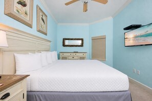 Un dormitorio con una cama grande, un tocador, un espejo y cuadros en la pared.