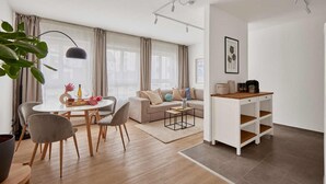 A modern living room with a dining area, a sofa set, a coffee table, and a small white cabinet.