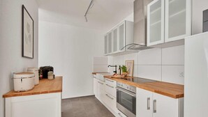 A modern kitchen with white cabinets, a wooden countertop, and a built-in oven.