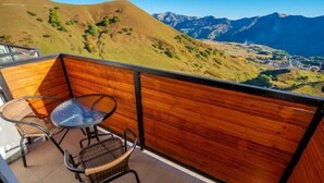 A balcony with a wooden partition, a glass table, and wicker chairs.