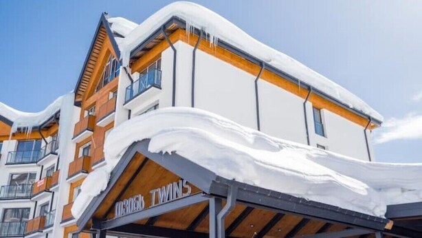 A modern hotel with a covered entrance and a snow-covered roof.