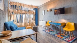 A modern living room with a sofa, chairs, a coffee table, a TV, and a wooden partition.