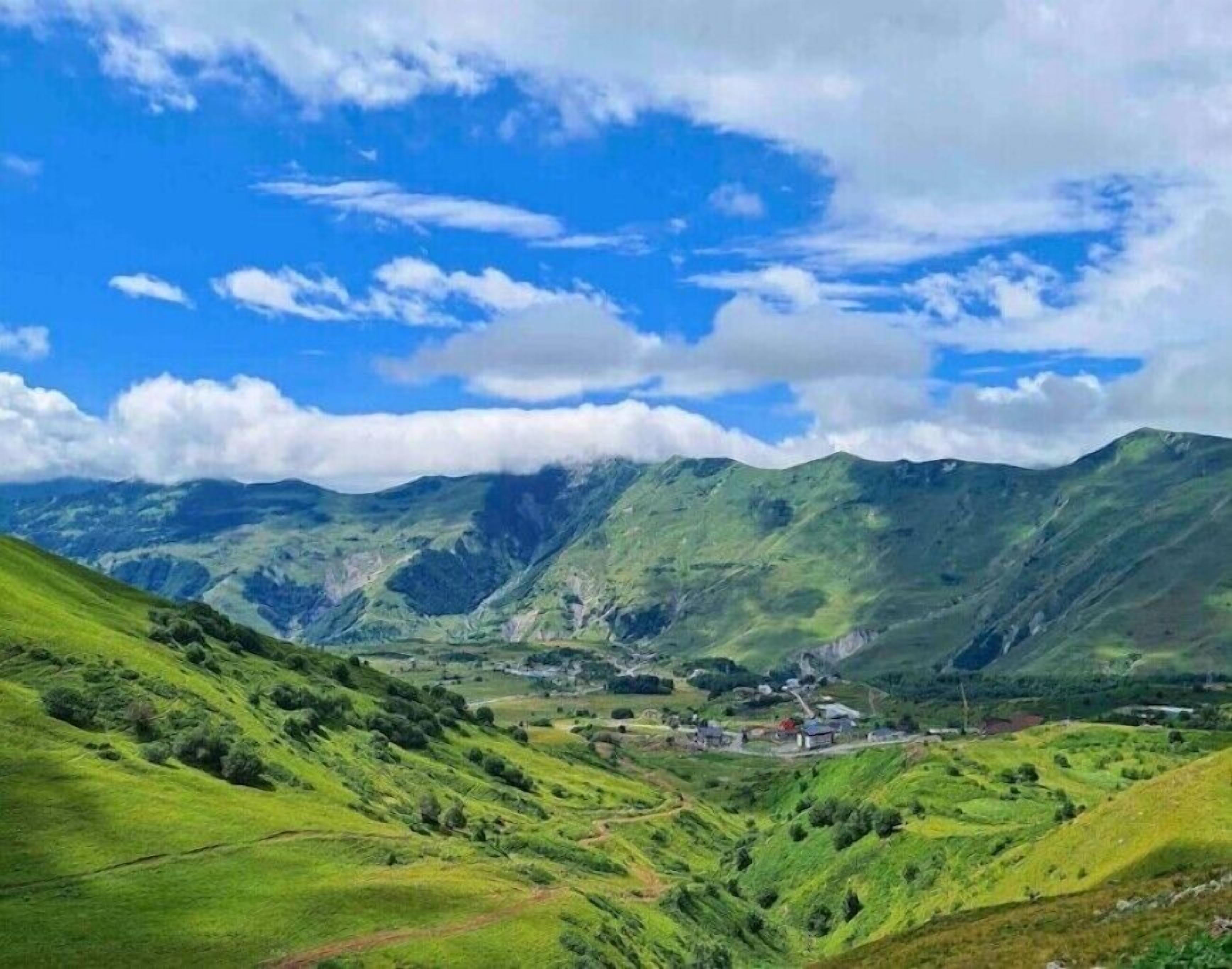 Una valle con dolci colline e un piccolo insediamento.