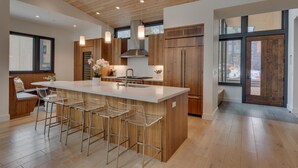 A modern kitchen with a large island, wooden cabinetry, and a seating area with bar stools. - Boulder Place Lookout At Northstar - TLUXP (Truckee)