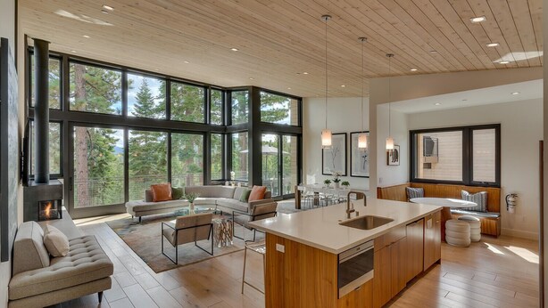A spacious living area with a large window, a fireplace, and a kitchen island. - Boulder Place Lookout At Northstar - TLUXP (Truckee)