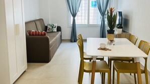 A modern living room with a sofa, a dining table with chairs, and a window with curtains. - BNBOOK MEDEA APARTMENTS 2 (Fuengirola)
