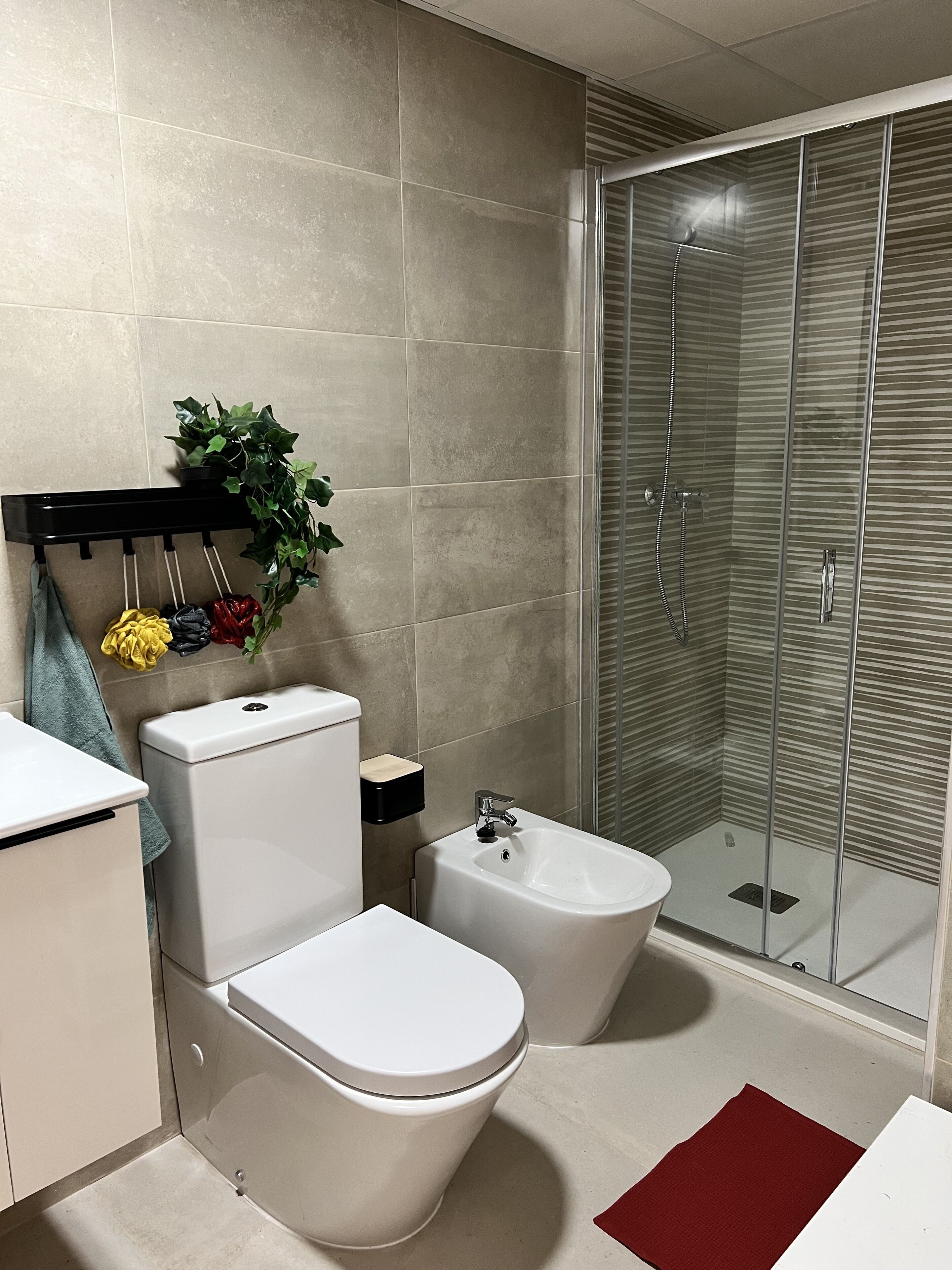 Un bagno moderno con toilette, bidet e cabina doccia in vetro.