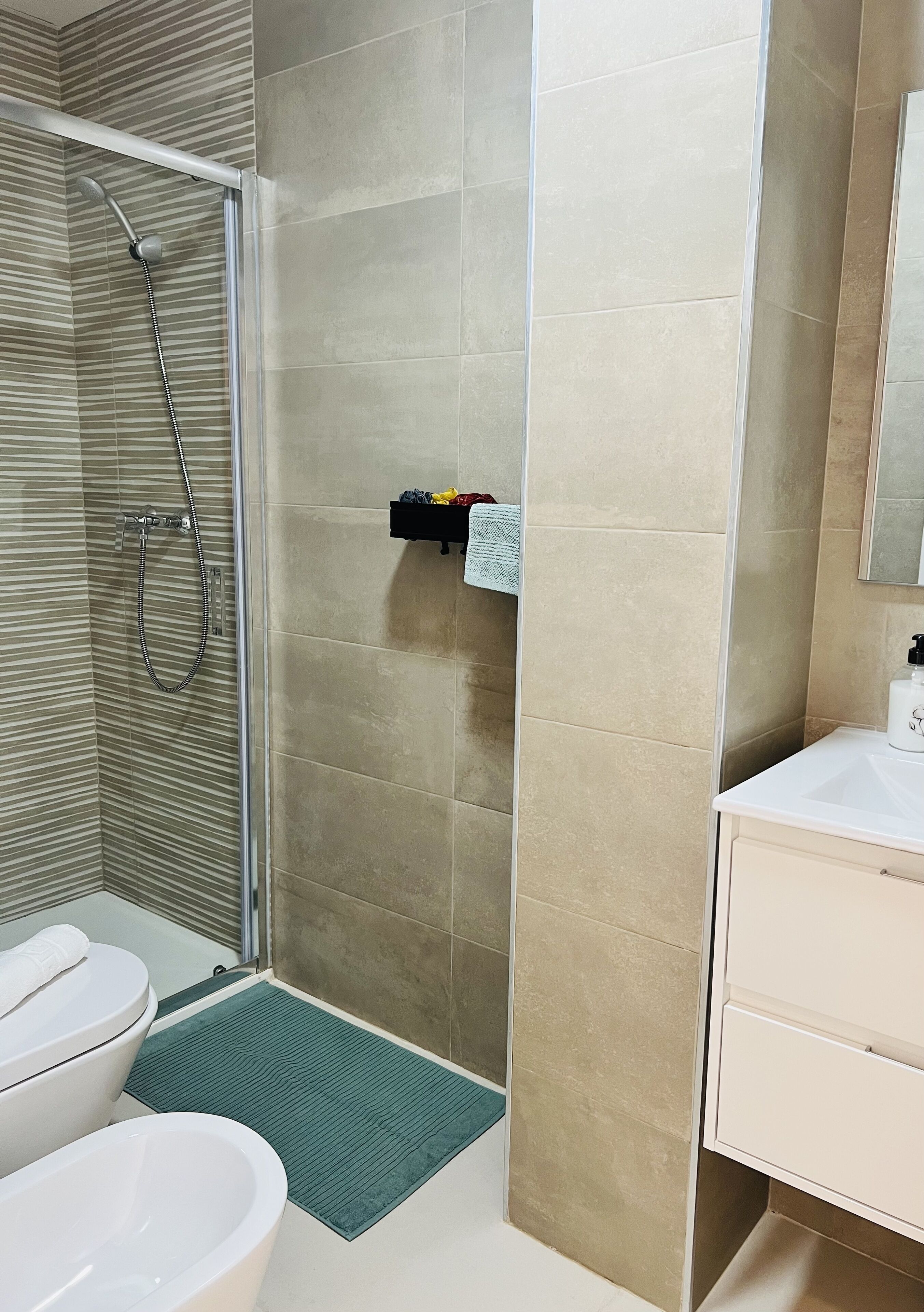 A modern bathroom with a glass shower enclosure, a white sink, and a toilet.