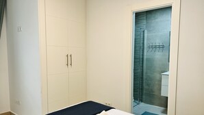 A bedroom with a bed, a wardrobe, and a bathroom visible through a glass door. - BNBOOK MEDEA APARTMENTS 2 (Fuengirola)