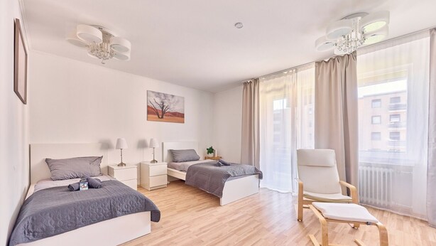 Ein modernes Hotelzimmer mit zwei Betten, einer Sitzecke und Blick auf die Stadt.