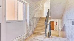 Eine Treppe mit Marmorwänden und Holzboden, die zu einer Tür oben führt.