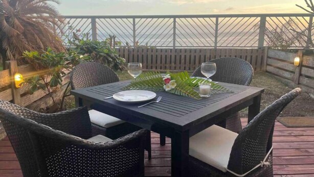 A table set for two with a view of the ocean at sunset. - Moehani Beach Lodge (Puna'auia)