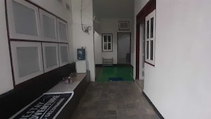 Un pasillo estrecho con un banco a la izquierda, un dispensador de agua y una puerta al final.