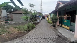 Un estrecho camino pavimentado bordeado por edificios residenciales con una entrada porticada a la derecha.