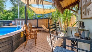 A poolside area with wooden deck, lounge chairs, and a barbecue setup. - Where Comfort Meets Class: Your Private 1B Luxury Retreat Awaits! (Largo)