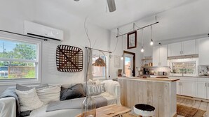 A modern kitchen with white cabinets, a wooden island, and a dining area with a rustic table and stools. - Where Comfort Meets Class: Your Private 1B Luxury Retreat Awaits! (Largo)