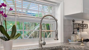 A kitchen with a double stainless steel sink, a modern faucet, and a window with blinds. - Where Comfort Meets Class: Your Private 1B Luxury Retreat Awaits! (Largo)