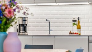 Ett modernt kök med en kaffebryggare, en diskho och en flaska olivolja på bänkskivan.