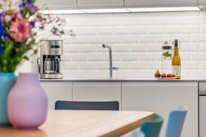 Moderni keittiö, jossa on kahvinkeitin, pesuallas ja pullo oliiviöljyä työtasolla.