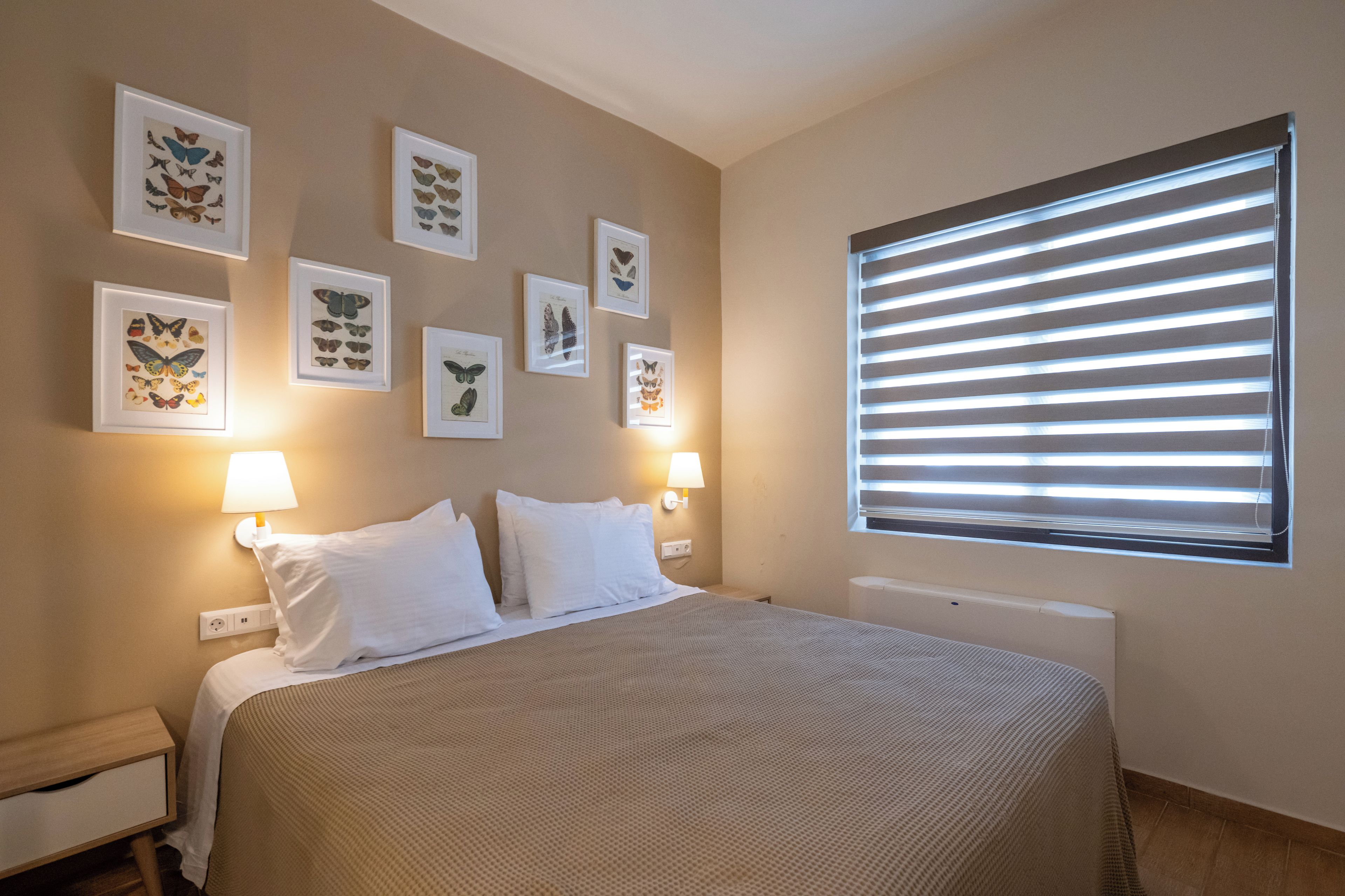 Una camera da letto ordinata con un letto grande, due lampade ai comodini e una finestra con persiane.