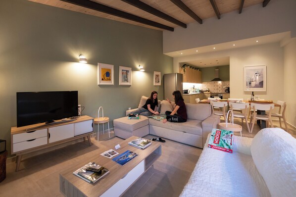 Un salon moderne doté d’un téléviseur à écran plat, d’un canapé, d’une table basse et d’un coin repas avec une table et des chaises.